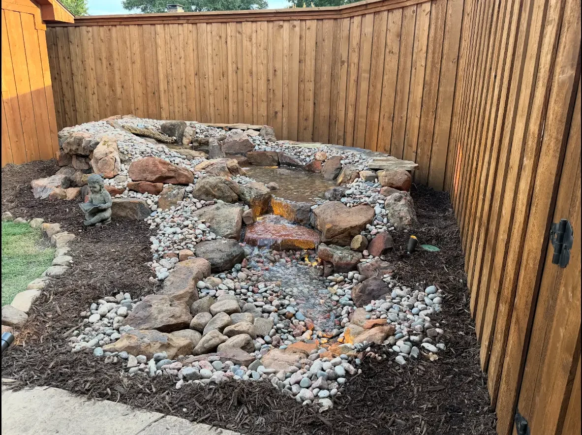 Completed backyard waterfall and stream built with natural stone and river rock