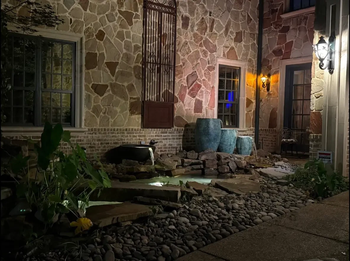 Finished pond and water feature lighting beside a stone home at night